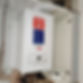 A white wall-mounted combi boiler neatly installed inside an open storage cupboard