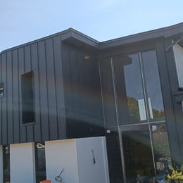 Modern two-story house with sleek black metal cladding and large glass windows