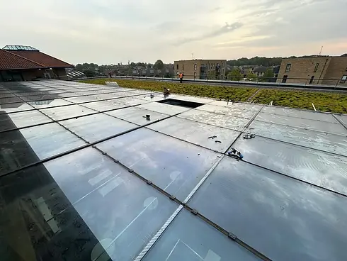 Rooftop view showing a reflective glass surface with a green roof section