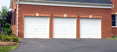 White garage doors are set in a red brick building