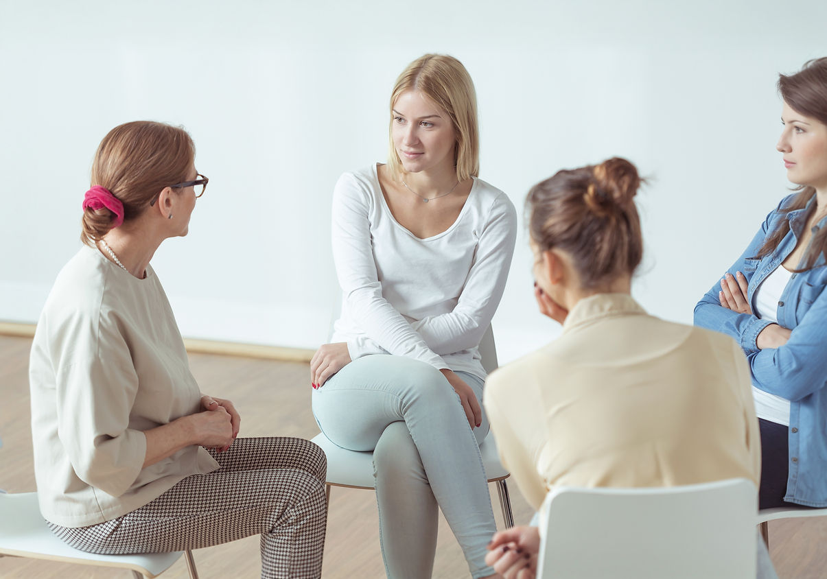 Four women sit in a circle, engaged in a thoughtful discussion