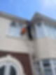 A man on a ladder cleaning the windows of a house, focused on maintaining the home's exterior appearance