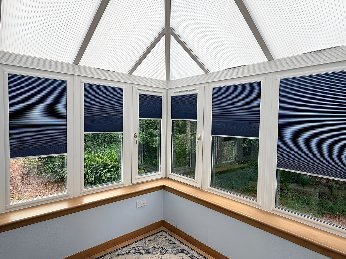 Modern grey pleated blinds installed across multiple conservatory windows letting in soft light