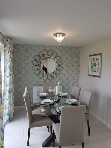 Dining room with patterned wallpaper and decorative round mirror