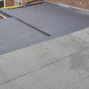 Flat roof close up. New felt installed next to older one.