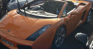 Orange convertible sports car parked in sunlight, showcasing sleek design and shiny rims