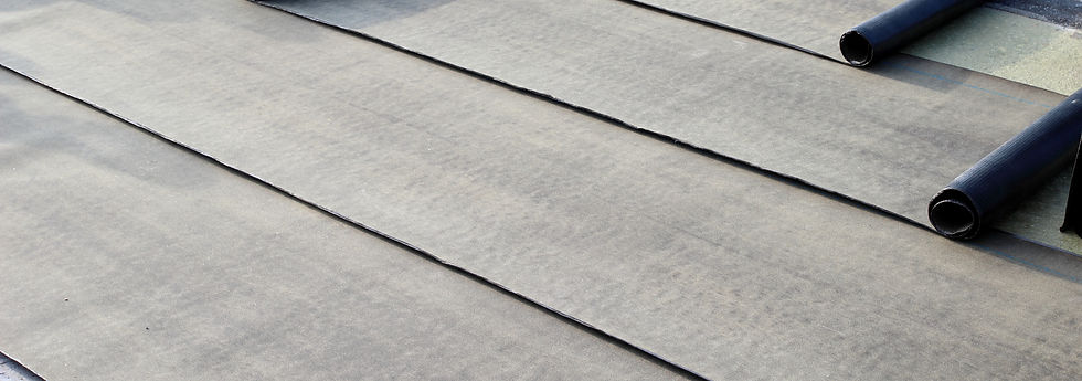 Rolled black roofing materials partially unrolled on a flat roof, highlighting the process of roof installation