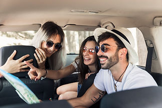 Young friends sitting inside the modern car looking at map