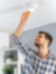 Man checking a ceiling-mounted fire alarm
