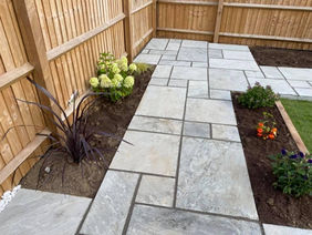 A serene garden featuring a stone walkway bordered by a rustic wooden fence