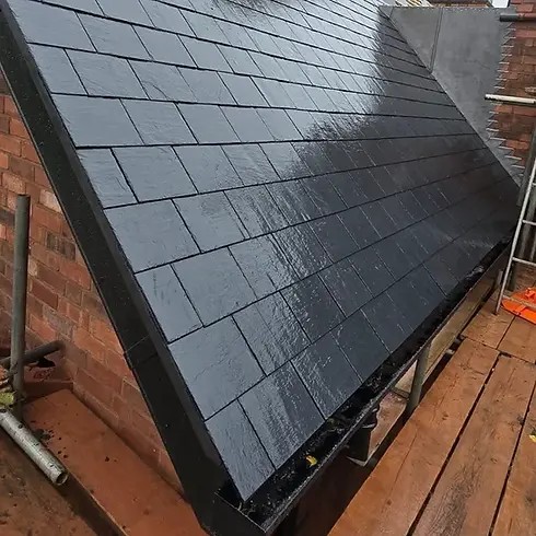 Sleek black slate tiles cover a sloped roofing structure, wet with raindrops.