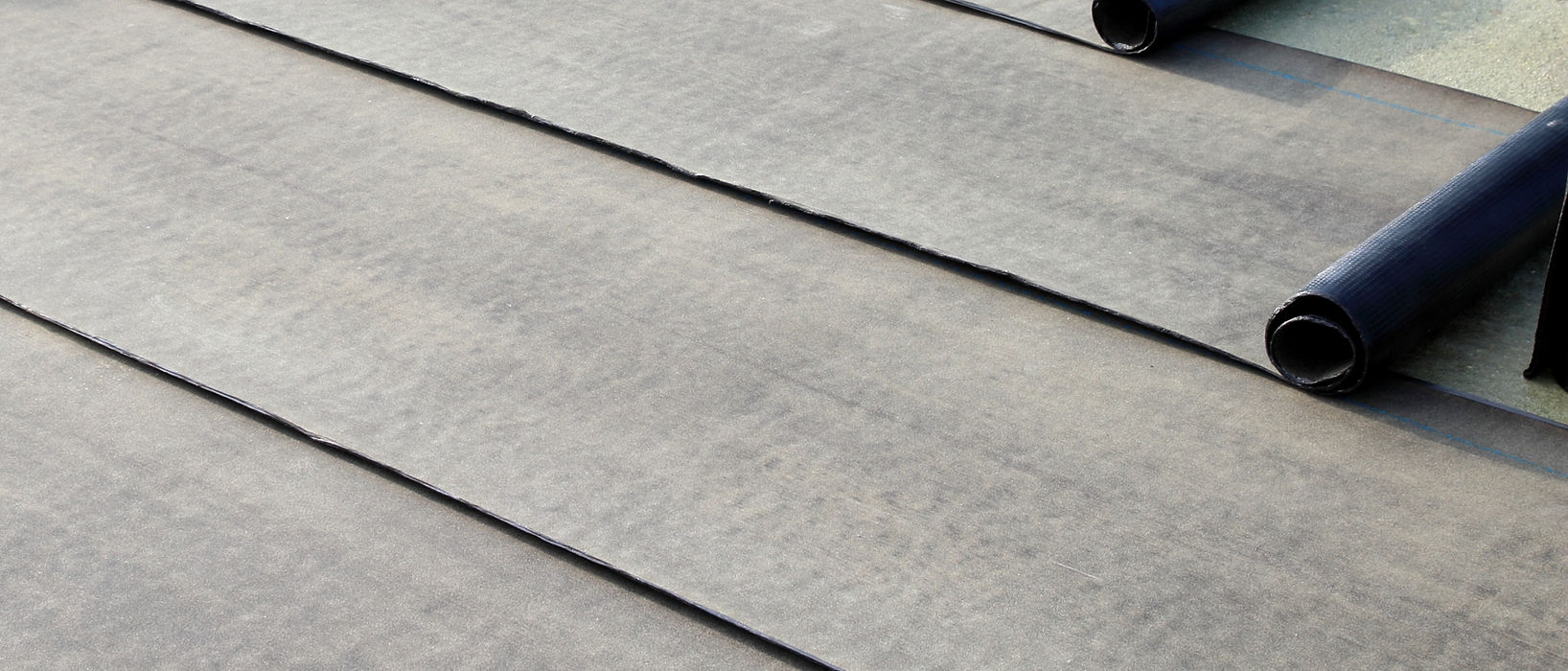 Dark roofing material partially unrolled on a flat surface
