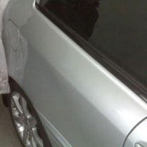 Silver car with plastic covering over the rear.