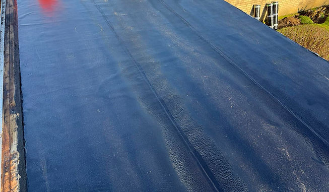 Flat roof covered in a smooth, dark membrane, in direct sunlight