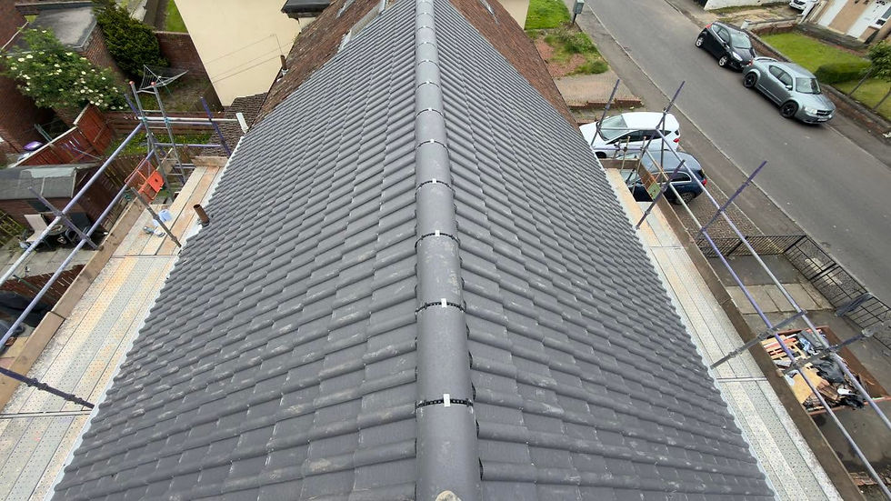 High-angle view of a newly retiled grey roof with dry ridge tiles, dry verge system, and surrounding scaffolding