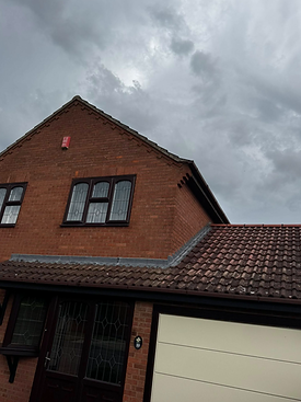 A traditional red brick house with arched windows and a lower roof section covered in red clay tiles