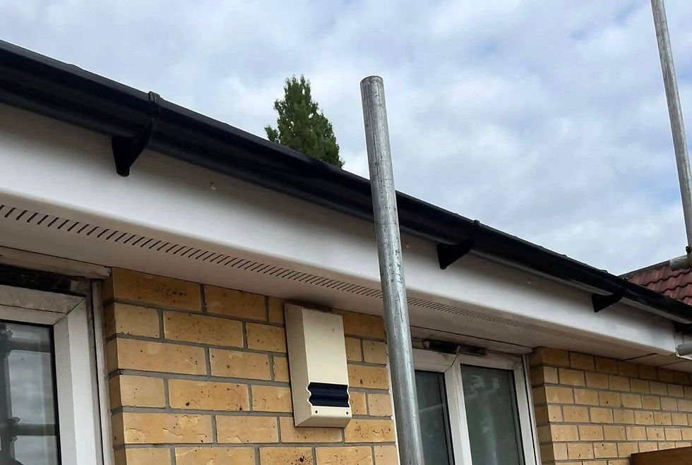 Newly installed black uPVC fascia, soffit, and guttering along white rendered wall edge