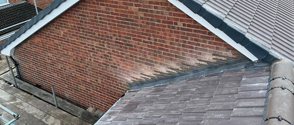 Gable end of a red brick house with dark grey dry verge caps and pitched roof tiles