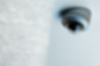 A ceiling-mounted security camera with a dark dome lens is positioned on a smooth