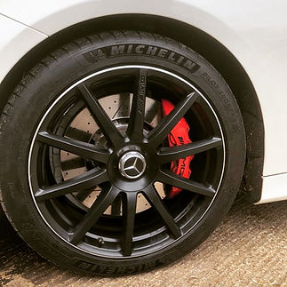 Close-up of a black Mercedes wheel with a Michelin tire, showcasing a red brake caliper