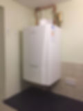 A white boiler installed in a small, enclosed room with minimal furnishings