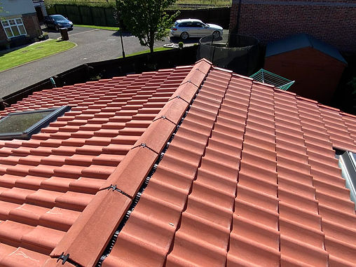 Red tiled roof with a visible skylight, under bright sunlight