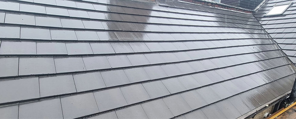 Wet grey slate roof tiles with raindrops, reflecting a blurred silhouette