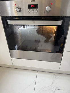 Stainless steel oven with digital clock displaying 12:01. Light inside reveals baking trays