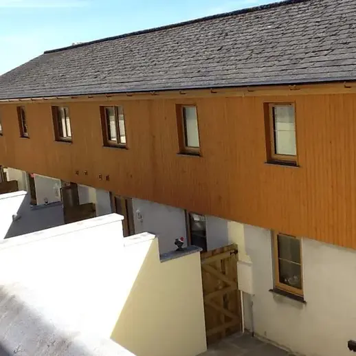 Finished building with upper-level orange wood vertical cladding