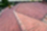 High-angle view of a complex hip roof covered in clean, red clay roofing tiles