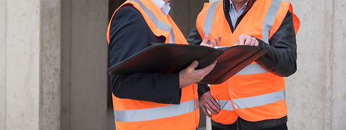 Two men wearing safety vests talking on construction site