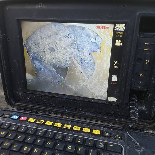 A portable drainage monitor displaying a close up texture scan of the inside of a damaged sewer pipe