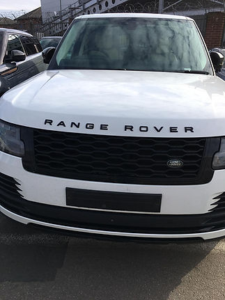Close-up of the front of a white Range Rover, focusing on the grille and logo