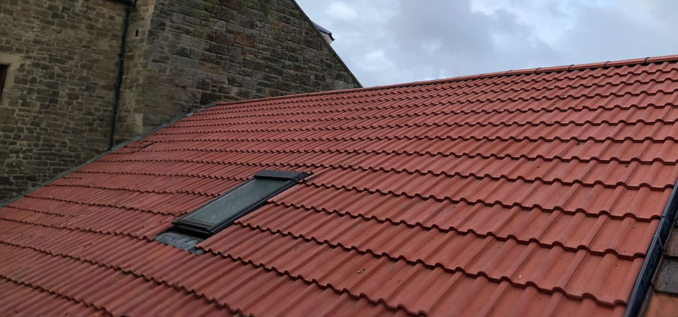 Red tiled roof with a skylight, adjacent to an old stone building with a steep gable