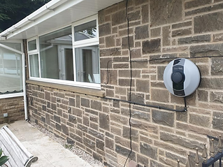 A brick house wall with a mounted electric vehicle charging station
