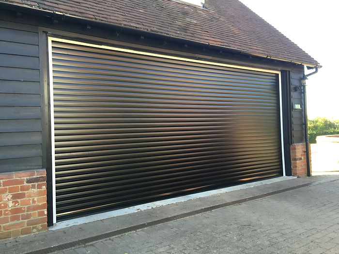leek black roller garage door on a brick-wall building, partially opens, reflecting sunlight