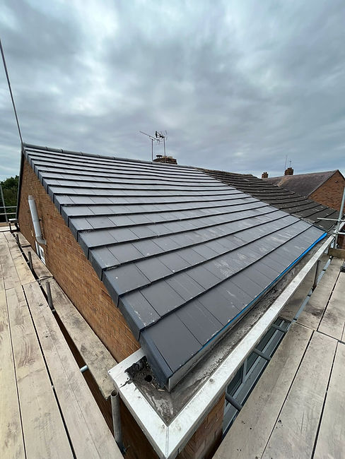 An elevated, side-angle view showing a sloped rooftop during a retiling project