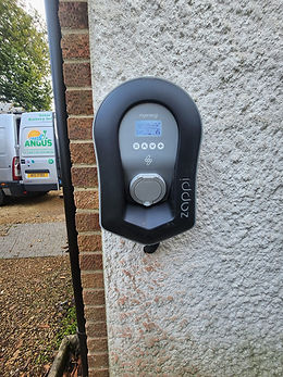 Electric vehicle charger on a brick and stucco wall, displaying buttons and screen
