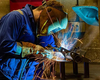Welder in protective gear welding metal with sparks
