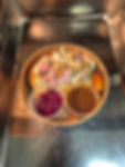 A round bowl of sliced turkey, stuffing, and a sausage is placed on a metal surface