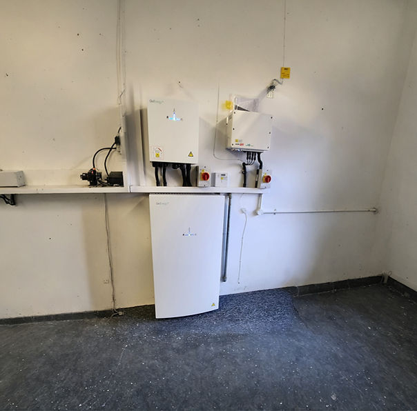 A room with electronic equipment mounted on a white wall, including control boxes and cables