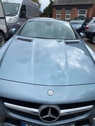Silver Mercedes-Benz sports car parked outside, front view showing emblem and grill