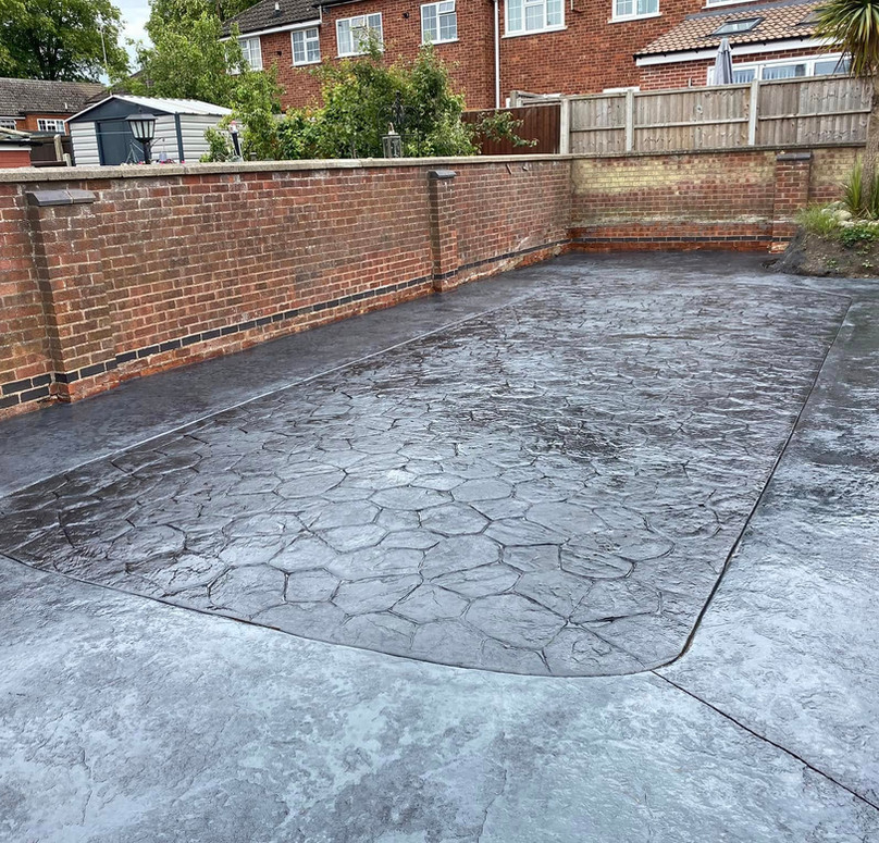 Outdoor patio with shiny wet concrete, bordered by a brick wall