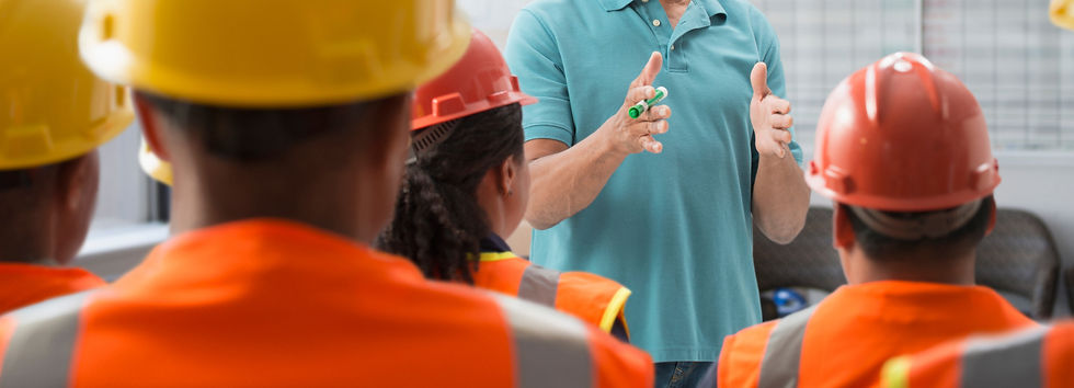 Construction worker wearing orange hard hat listening to a presentation on site