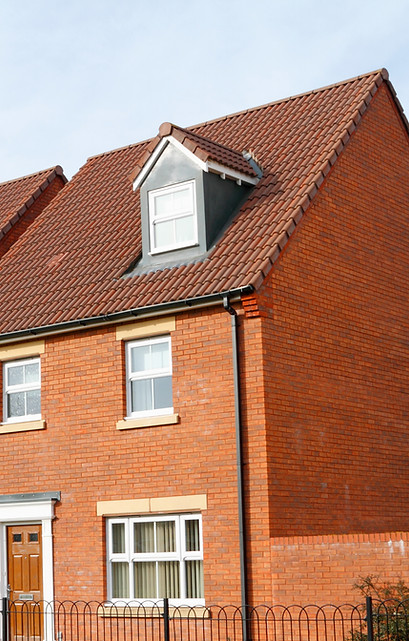 Brick house with a red-tiled roof, dormer windows, and a white-framed front doo