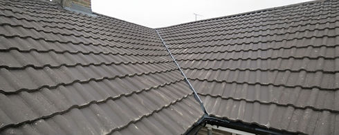 A close-up of a gray tiled roof, showcasing overlapping shingles and a central valley