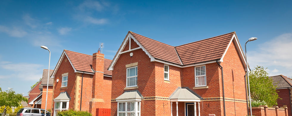 A sunny suburban street with two red-brick houses. Both have gabled roofs