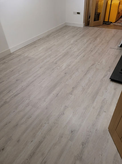 A broad view of light grey wood-grain vinyl flooring installed across a large room