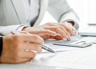 Close-up of hands typing on a calculator, set on white paperwork with graphs