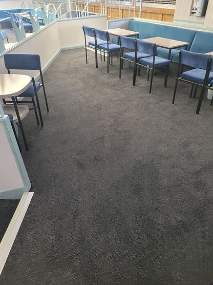 Durable grey commercial carpeting installed in an office or hospitality area with tables and chairs